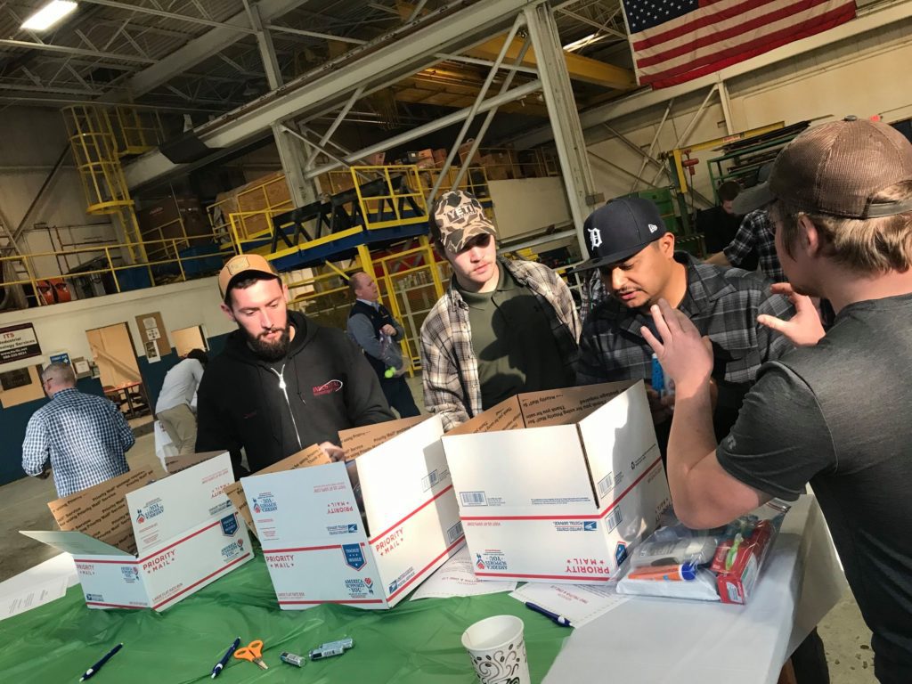 Team members collaborating on assembling care packages for U.S. troops during an Operation Military Care team building event.