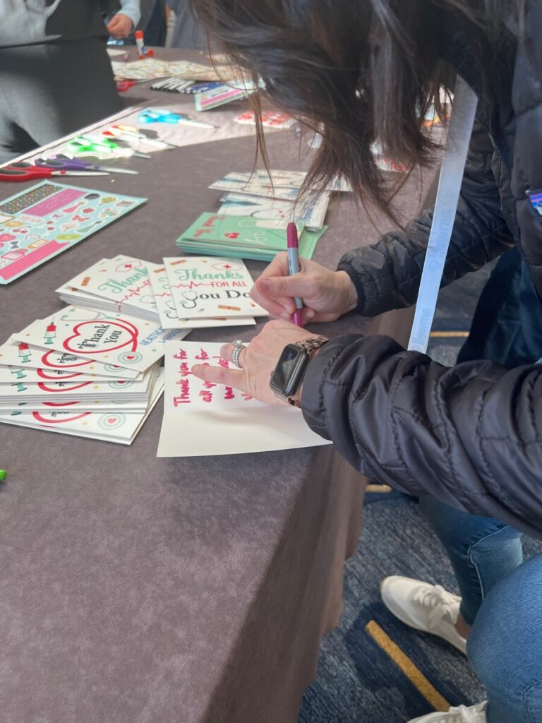 A participant writing heartfelt thank-you notes to healthcare workers during the Healthcare Heroes scavenger hunt team building activity.